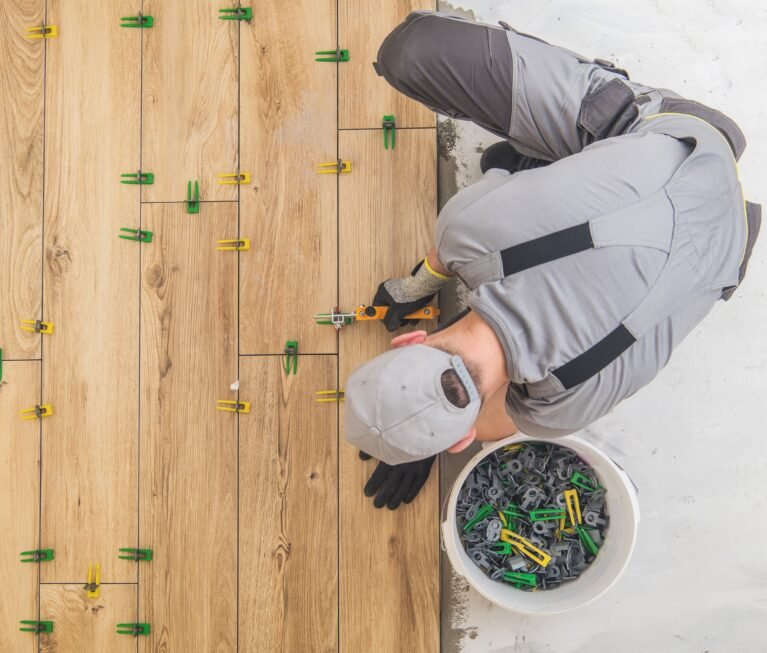 Ceramic Tiles Floor Installer. Wood Like Looking Tiles Installed by Professional Caucasian Construction Interior Finishing Worker. Flooring Industrial Theme.