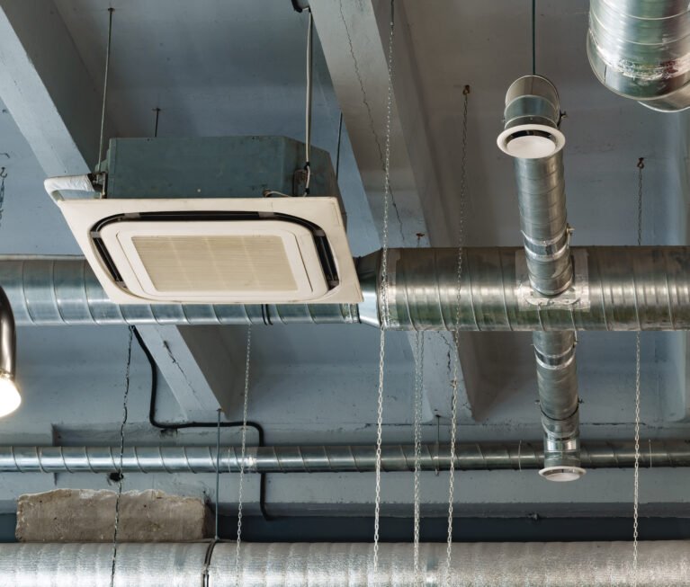 Silver ventilation pipes hanging from the ceiling inside the building close up